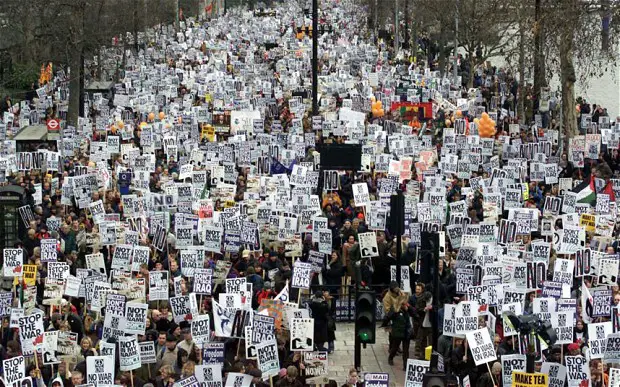 Large pressure group of anti-war protesters holding protest signs